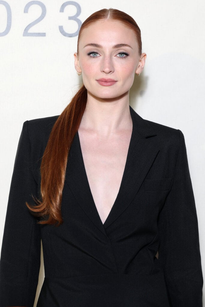 Sophie Turner wears a dark V-neck.