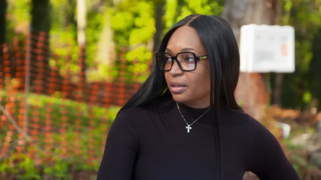 Marlo Hampton wears glasses and all black outdoors.