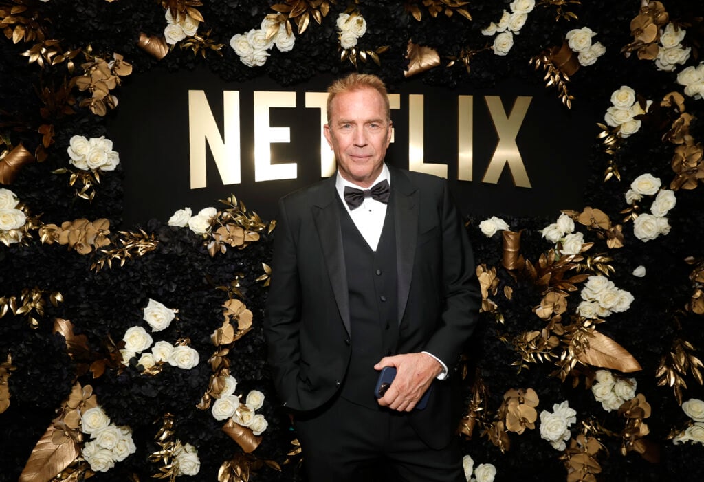 Kevin Costner in front of a glittering Netflix logo.