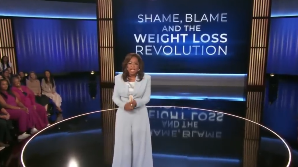 Oprah Winfrey stands in a town hall format with a 