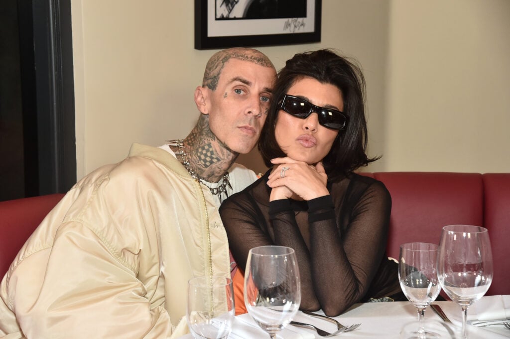 Travis Barker and Kourtney Kardashian pose for a photo while eating at a restaurant.